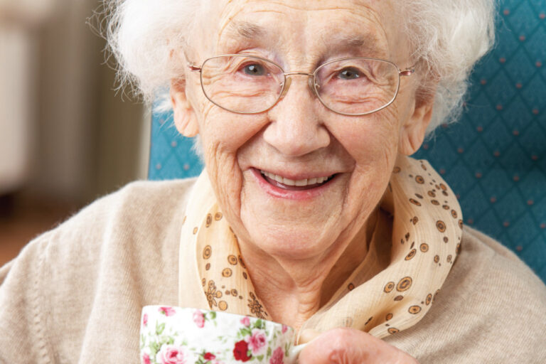 Happy senior woman sipping a warm cup of tea